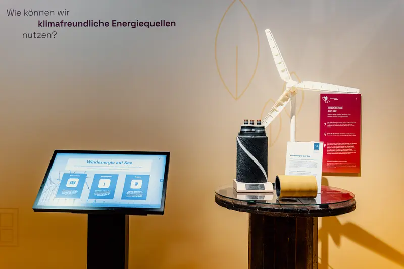 Das Bild zeigt einen Bildschirm und einen Sockel auf dem das Modell eines Windrades steht.