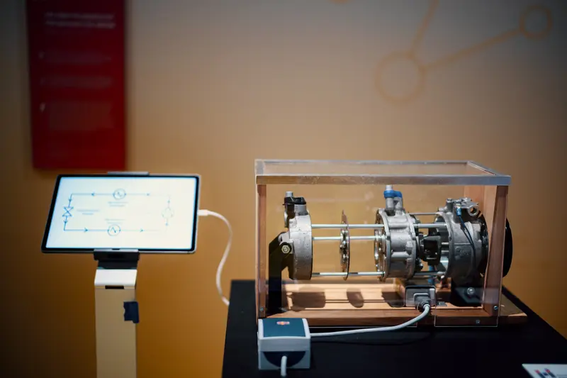 Das Bild zeigt den Kältemittelverdichter einer Wärmepumpe und ein Tablet mit einer erklärenden Graphik.