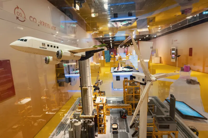 Das Bild zeigt eine Legostadt mit einem Flugzeug und einem Windrad.